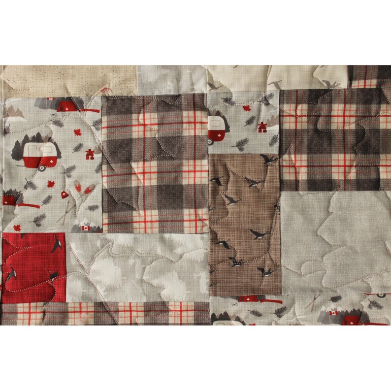 May include: A patchwork quilt with a variety of fabrics, including plaid, floral, and geometric patterns. The quilt is quilted with a leaf design and features a red, white, and blue color scheme.