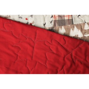 May include: Close-up of a red quilted fabric with a leaf pattern. The fabric is soft and has a subtle sheen.
