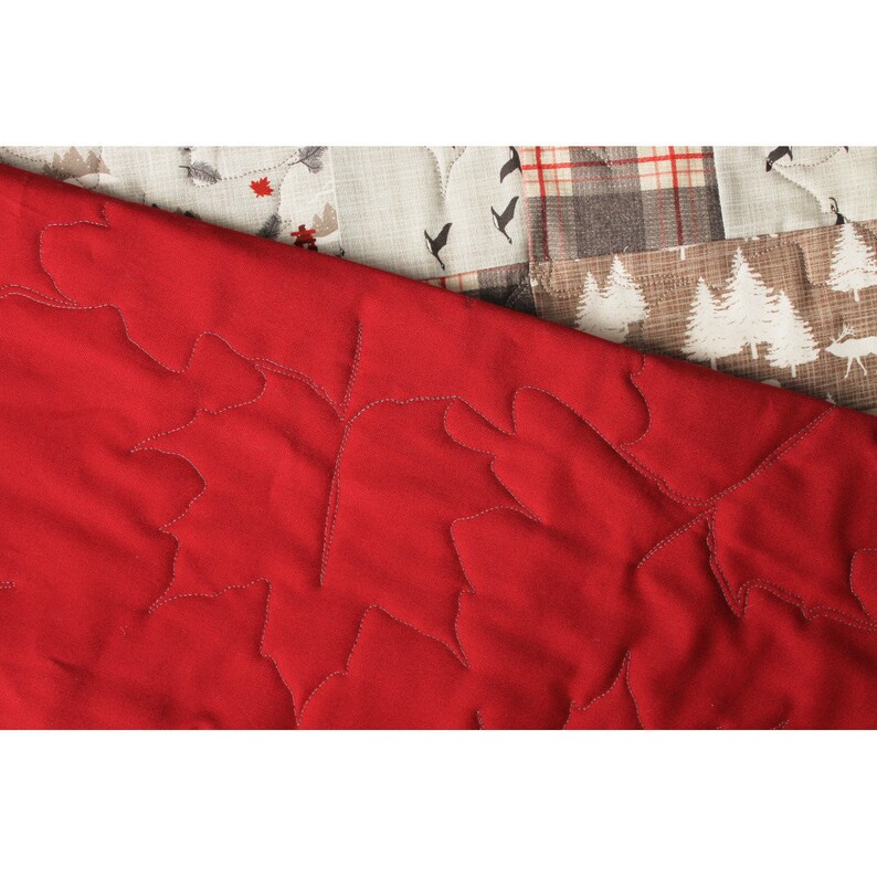 May include: Close-up of a red quilted fabric with a leaf pattern. The fabric is soft and has a subtle sheen.