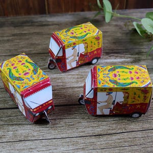 A decorative wedding tablescape with a striking red rickshaw favor box filled with gold-wrapped chocolates for guests.