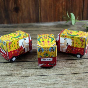 Three bright red rickshaw (tuktuk) boxes in a row, each featuring traditional patterns on a flat pack sheet ready for assembly.