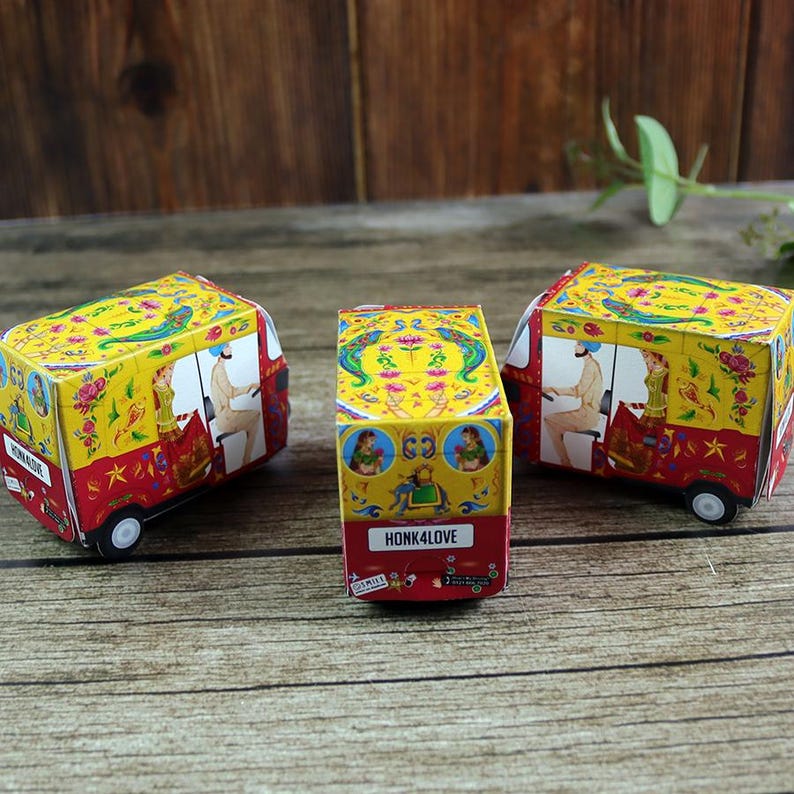 Three bright red rickshaw (tuktuk) boxes in a row, each featuring traditional patterns on a flat pack sheet ready for assembly.