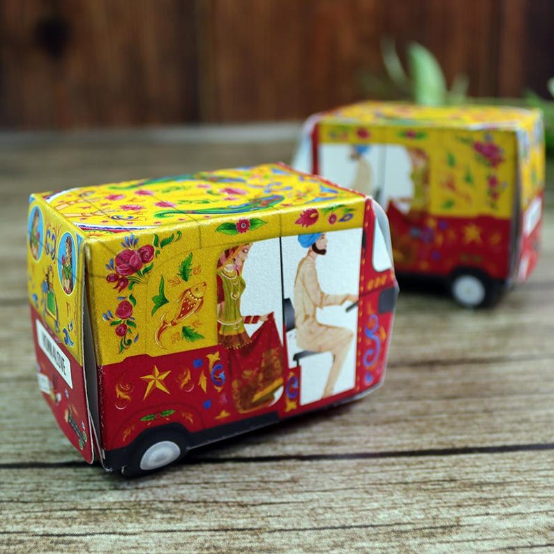A vibrant red, handmade rickshaw-shaped favor box, perfect for adding a bold pop of color to your wedding guest tables.