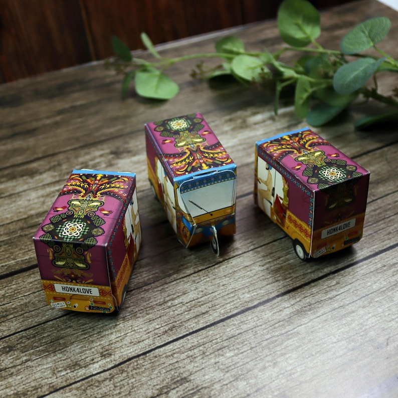 Three colorful handmade rickshaw boxes in a row, showcasing their detailed design and perfect size for wedding favors (8.5cm x 5cm x 4cm).