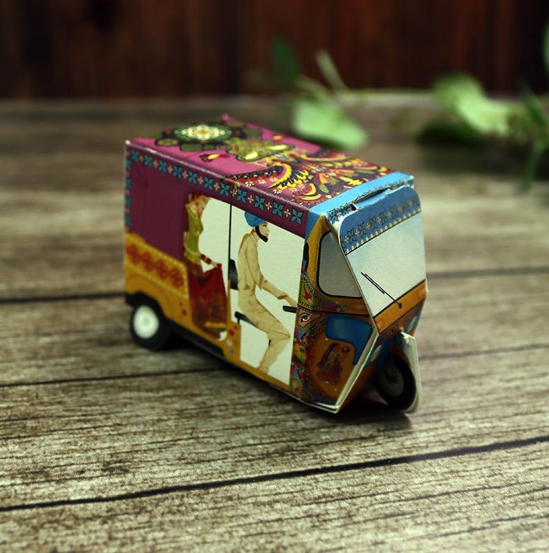 A vibrant and intricate rickshaw (tuktuk) gift box on a decorative tray, ready to be filled with mehndi cones or sweets.