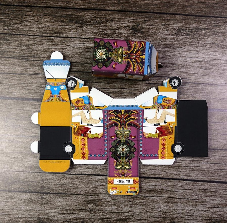 A bright yellow and purple rickshaw, flat, unassembled favor box positioned on a table, symbolizing a unique and memorable wedding favor.