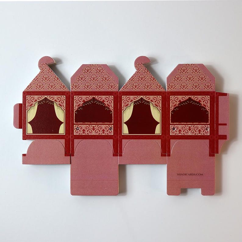 Puede incluir: Caja decorativa plana y desplegada, con una combinaci&oacute;n de colores rojo y rosa. La caja presenta un dise&ntilde;o ornamentado con ventanas arqueadas y un techo estampado. La direcci&oacute;n del sitio web, SEADICARDS.COM, est&aacute; impresa en la caja.