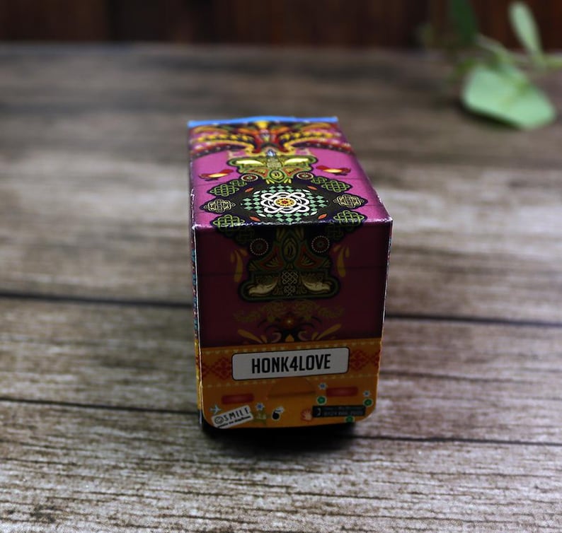 Close-up side view of a detailed rickshaw favor box, highlighting its iconic shape, traditional patterns, and wheels.