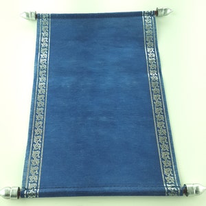 May include: A blue scroll with silver detailing. The scroll features a silver border with an intricate pattern. It is held by silver rods at the top and bottom. The scroll is made of textured fabric.