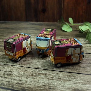 A wedding table setting featuring a small, decorative rickshaw box placed beside a plate, filled with festive confetti.