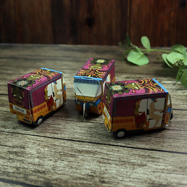 A wedding table setting featuring a small, decorative rickshaw box placed beside a plate, filled with festive confetti.