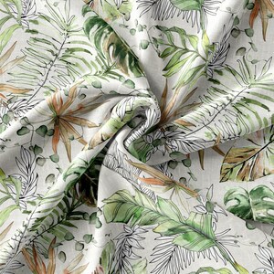 May include: A white fabric with a green, brown, and black tropical leaf pattern. The fabric is crumpled and has a textured surface.