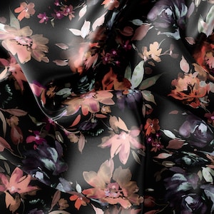 May include: Black satin fabric with a watercolour floral print in shades of pink, orange, and purple. The fabric is draped and folded, showing the texture and pattern.