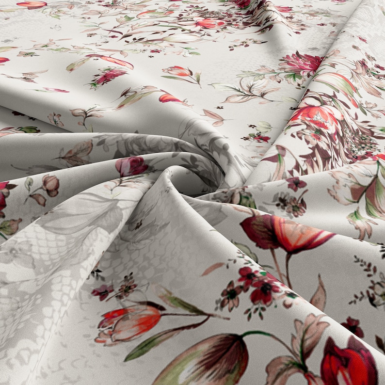 May include: White fabric with a floral print featuring red, pink, and green flowers. The fabric is folded and draped, showcasing the pattern.