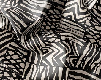 May include: Black and white abstract patterned fabric with a geometric design. The fabric is made of a soft, silky material and has a subtle sheen.