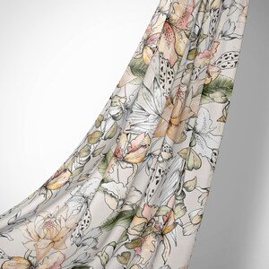 May include: A white fabric with a floral pattern in shades of pink, orange, and green. The fabric is draped over a white background.