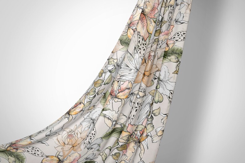 May include: A white fabric with a floral pattern in shades of pink, orange, and green. The fabric is draped over a white background.