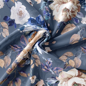 May include: A blue fabric with a floral print featuring white, brown, and blue flowers. The fabric is folded and the flowers are in focus.