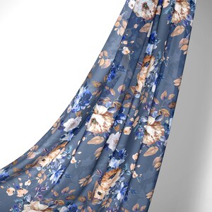 May include: A blue fabric with a floral pattern featuring white, brown, and blue flowers. The fabric is draped over a white background.