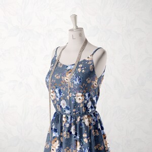 May include: A blue floral print dress with a white background and brown accents. The dress is on a white mannequin with a measuring tape around the neck. The tape reads "L 12".