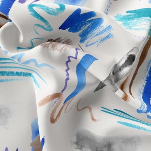 Op de afbeelding: Witte stof met een abstract aquarelpatroon in blauw, turquoise, bruin en paars. De stof is gekreukt en gevouwen.