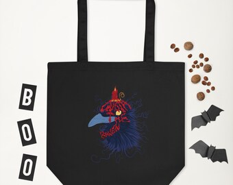 Puede incluir: Bolsa de tela negra con un gráfico de una cabeza de cuervo con una vela encendida en la parte superior. La cabeza del cuervo está formada por la palabra "Raven" en letras rojas. La bolsa tiene un asa negra.