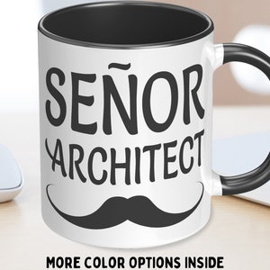 May include: White ceramic coffee mug with a black handle. The mug has black text that reads "SEÑOR ARCHITECT" with a black mustache underneath.
