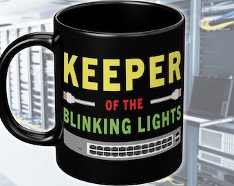 May include: Black ceramic mug with the text "KEEPER OF THE BLINKING LIGHTS" in yellow and green. The mug features a graphic of a network switch with ethernet cables.