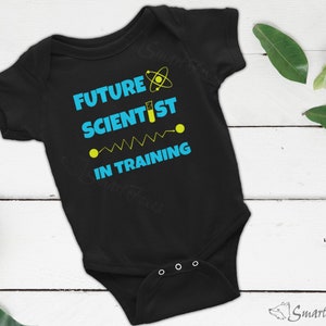 May include: Black baby onesie with the text "Future Scientist in Training" in blue and yellow. The onesie has a small atom symbol in blue and a test tube symbol in yellow.