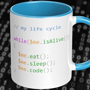 Pode incluir: Caneca de cerâmica branca com borda e alça azul claro. A caneca apresenta um trecho de código que diz "// my life cycle while($me.isAlive()) { $me.eat(); $me.sleep(); $me.code(); }" em diferentes cores.