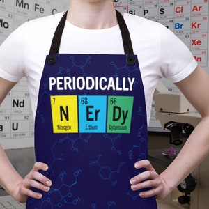 May include: A blue apron with a white text overlay that reads "PERIODICALLY". The apron features three colorful squares with the chemical symbols N, Er, and Dy, representing the elements nitrogen, erbium, and dysprosium.