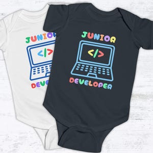 May include: Two baby onesies, one white and one black, with the text "Junior Developer" and a colorful cartoon laptop with code symbols on the screen.