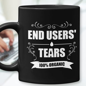 Könnte beinhalten: Schwarze Keramik-Kaffeetasse mit weißem Text, der "End Users' Tears 100% Organic" lautet.