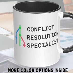 May include: White ceramic mug with a black rim and handle. The mug features a graphic of a tree with branches and leaves in green, blue, and pink. The text "CONFLICT RESOLUTION SPECIALIST" is printed on the mug.