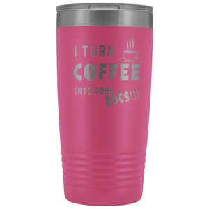 以下が含まれることがあります： 銀色の蓋が付いたピンクのステンレス製タンブラー。タンブラーには「I turn coffee into code bugs!」という文字が刻まれています。