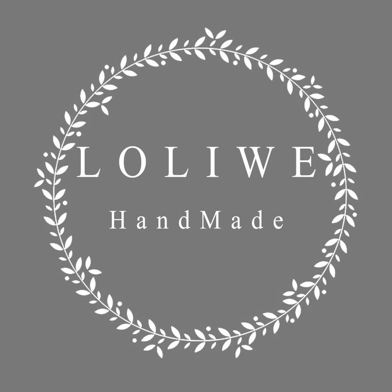 May include: A circular wreath graphic composed of white leaves and small berries on a solid gray background. The text LOLIWE is centered in white capital letters, with the word HandMade positioned directly below in white title case lettering.