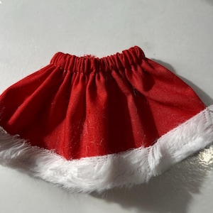 May include: Red skirt with white fur trim. The skirt is made of a soft, red fabric and has a white fur trim around the bottom.