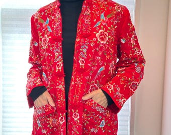 May include: A red embroidered jacket with floral and bird designs. The jacket has a mandarin collar and a button closure.