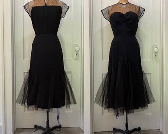 May include: A black vintage dress with a tulle skirt and a sheer bodice with polka dots. The dress is on a mannequin and has a fitted bodice and a full skirt.