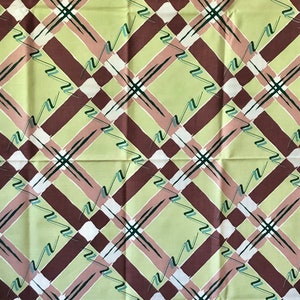 May include: A green, brown, and white plaid fabric with a repeating pattern of diagonal lines and zigzags.