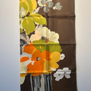 May include: A rectangular brown silk scarf with a floral design. The flowers are in shades of yellow, orange, white, and gray. The scarf has a dark brown border and a light gray trim.