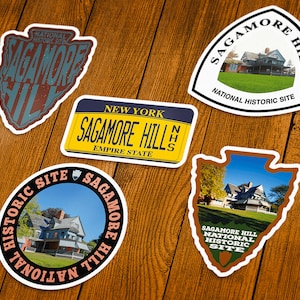 May include: A collection of Sagamore Hill stickers in various shapes, including a license plate design and an arrowhead shape. The stickers feature images of the historic site and text that reads "Sagamore Hill National Historic Site."