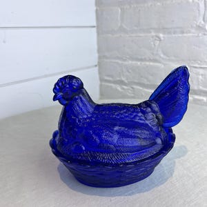 May include: A set of three ceramic mugs with a speckled, matte finish. The mugs are in shades of cream, light brown, and dark brown. Each mug has a simple, minimalist design and a rounded handle.