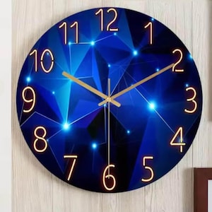 May include: Round wall clock with a blue geometric design. The clock face features gold-colored numerals and hands, with a dark blue background. The design includes interconnected lines and glowing dots.