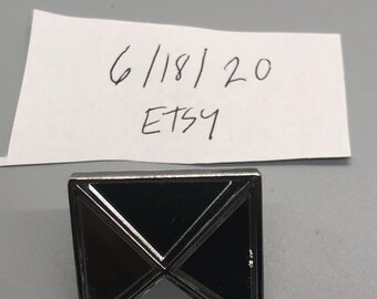 May include: A silver-toned metal square with a mirrored surface. The square is divided into four triangles, with the center triangle being mirrored and the other three triangles being black. The square has a beveled edge. The image also includes a handwritten note that says "6/18/20 Etsy".