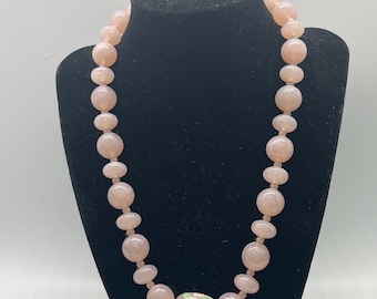May include: A pink beaded necklace with a large pink and white floral pendant.