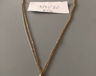 May include: A gold chain necklace with a small gold elephant pendant with clear rhinestones. The necklace is layered with two chains.