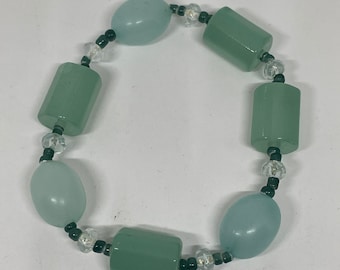 May include: A bracelet made with light blue and green oval and rectangular beads, interspersed with black and clear round beads.