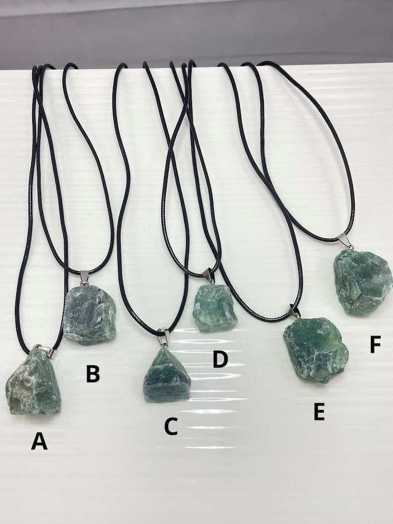May include: Six green gemstone necklaces with black cords. The gemstones are different shapes and sizes. The necklaces are labeled A through F.