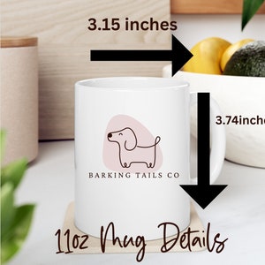 May include: White ceramic mug with a pink and brown illustration of a dachshund and the text "Barking Tails Co." The mug is 3.74 inches tall and 3.15 inches wide. It is a 11oz mug.